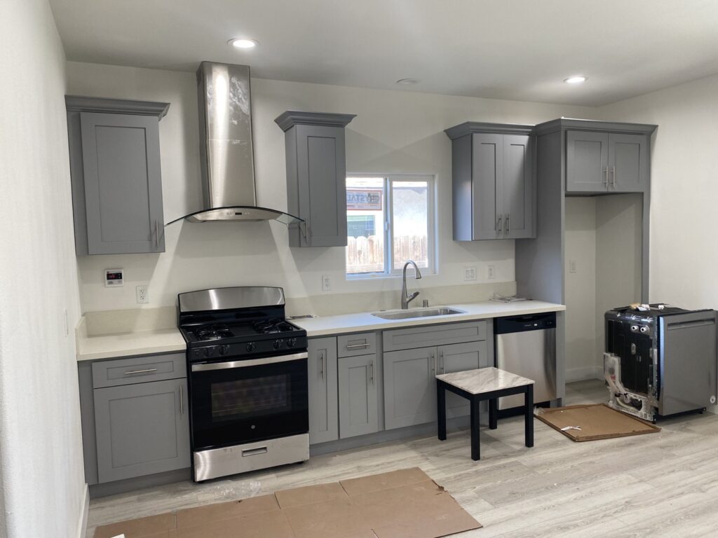 Finished kitchen with gray cabinets and range hood